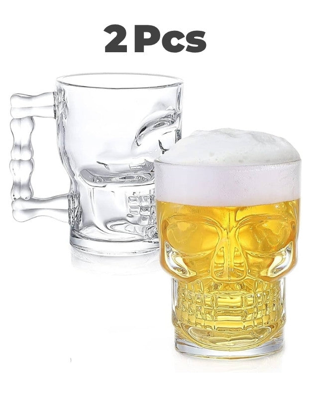 Two skull-shaped glass mugs with one filled with beer on a white background.