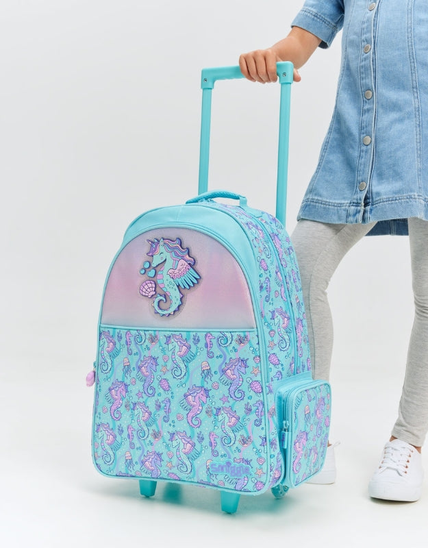 Girl holding Smiggle Seahorse Unicorn trolley backpack with light up wheels in aqua and pink design