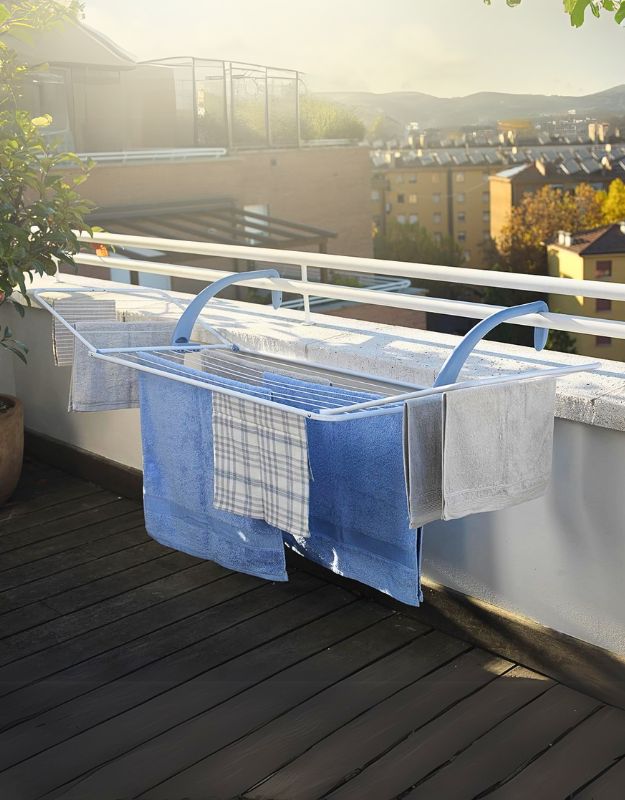 A balcony dryer with white and blue colors, featuring adjustable and foldable resin wings, mounted on a balcony with clothes drying on it.