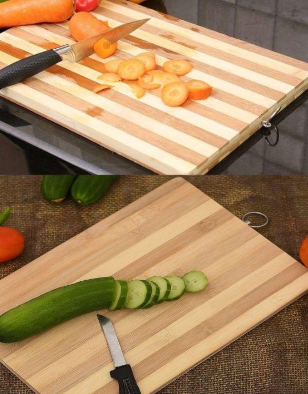 Wooden cutting boards with sliced vegetables and knives on a kitchen counter. Wooden bamboo cutting boards used for slicing carrots and cucumbers with knives.