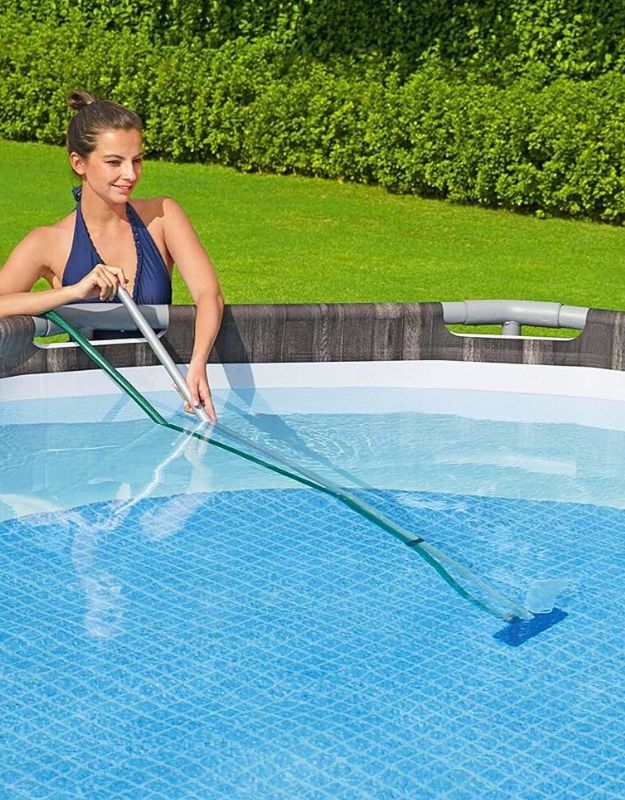 Woman cleaning above ground pool with Bestway 58013 pool vacuum head and telescopic pole