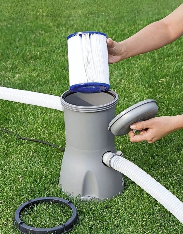 Person inserting a Bestway 58094 Type II cartridge filter into a gray pool pump system outdoors on the grass.