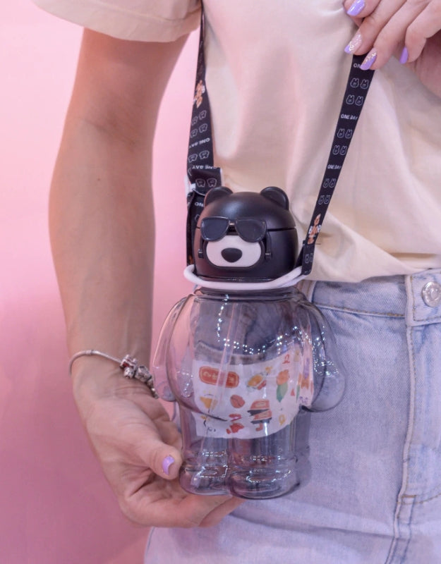 Model holding black bear-shaped water bottle with sunglasses and black strap, 850ml.
