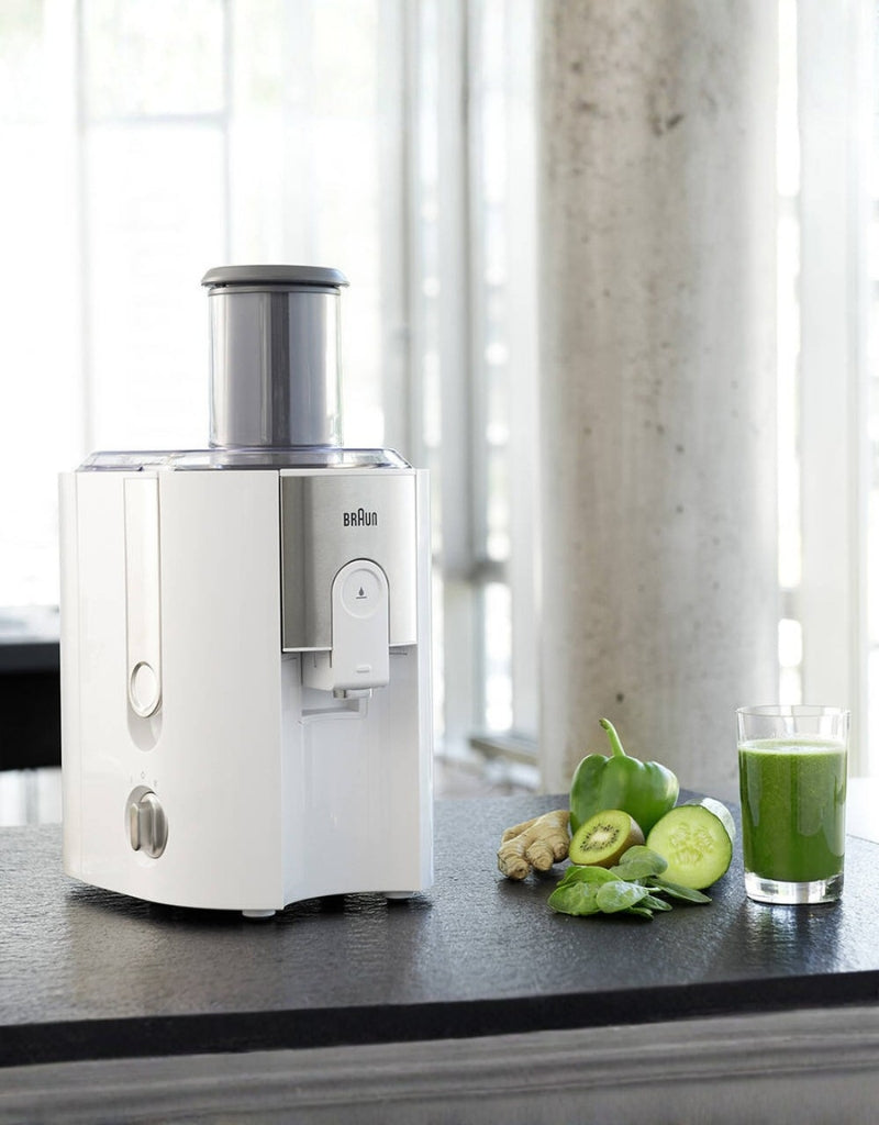 Braun J500 spin juicer on kitchen counter with fresh green juice and vegetables
