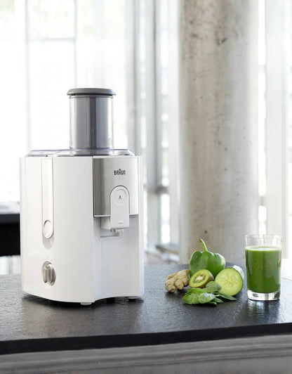 Braun J500 spin juicer on kitchen counter with fresh green juice and vegetables