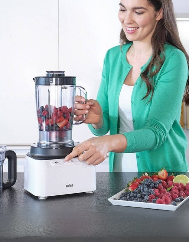 Woman using Braun PurEase blender with fresh berries.
