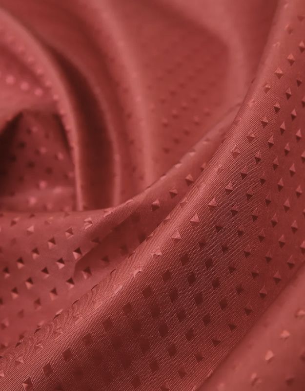 Red shower curtain fabric with triangle embossed pattern.