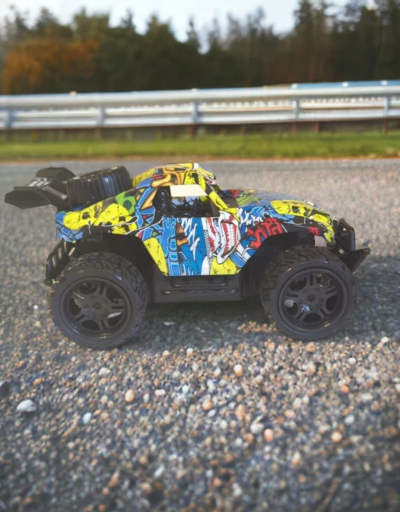 Side view of the Car King 1:16 RC mountain car with colorful graffiti body on a road.