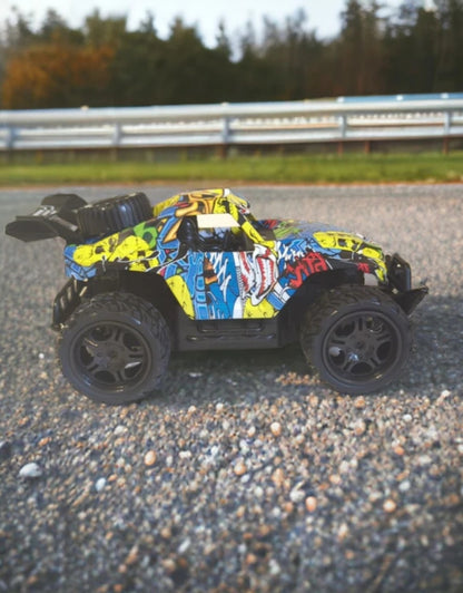 Side view of the Car King 1:16 RC mountain car with colorful graffiti body on a road.