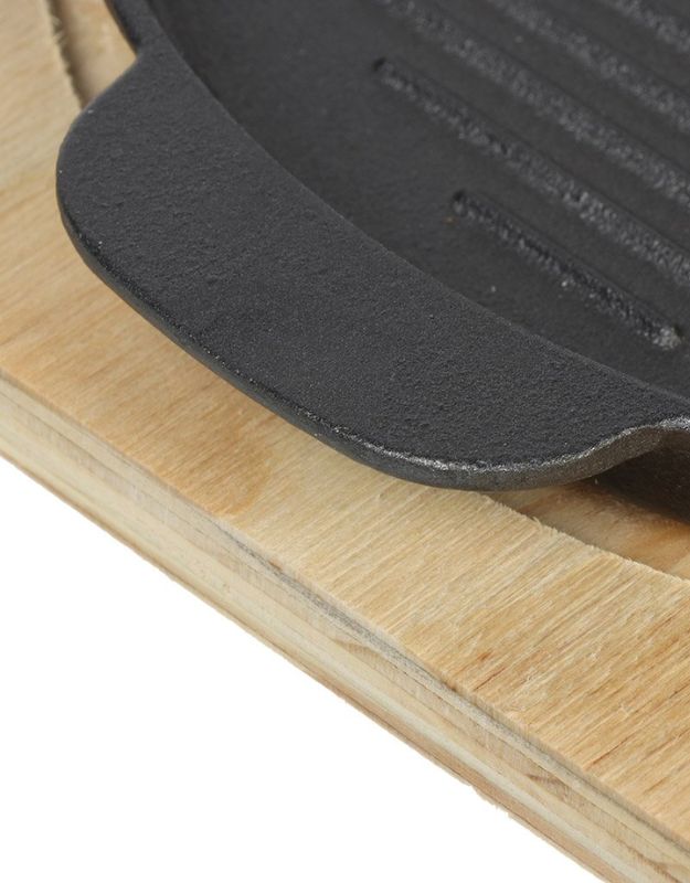 Close-up of a black rubber mat on a wooden surface. Close-up of cast iron grill pan handle resting on wooden base, highlighting sturdy design.