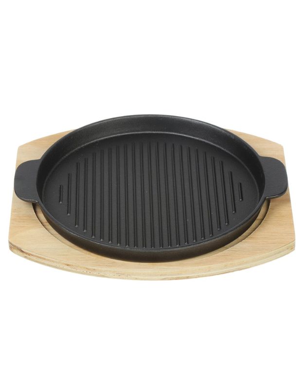 Black grill pan on a wooden stand against a white background. Black cast iron grill pan with wooden base, durable and heat-resistant cookware for home or restaurant use.