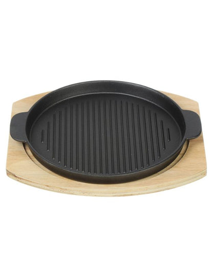 Black grill pan on a wooden stand against a white background. Black cast iron grill pan with wooden base, durable and heat-resistant cookware for home or restaurant use.