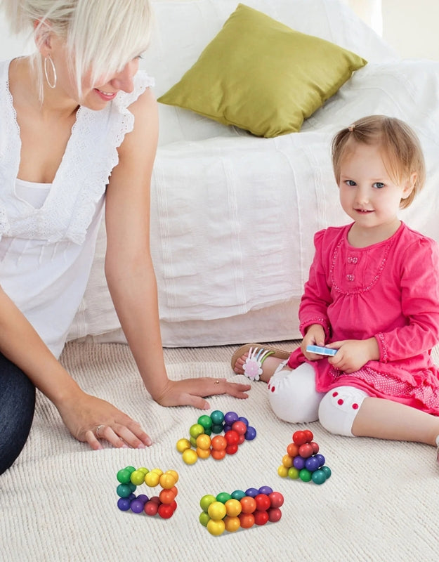 A lifestyle shot of a child sitting on the floor and playing with the multi-colored magnetic balls and sticks.