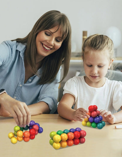 A lifestyle shot of a child's hands and legs visible on a light-colored floor, playing with the magnetic ball and stick set.