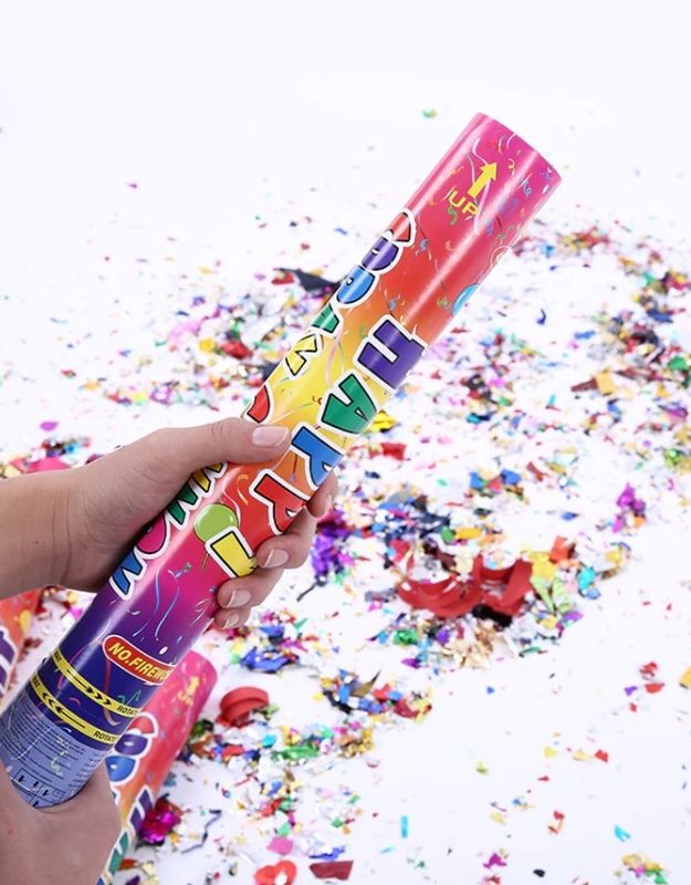 A person holding a multicolored confetti spray canon that has been activated, sending out colorful confetti.