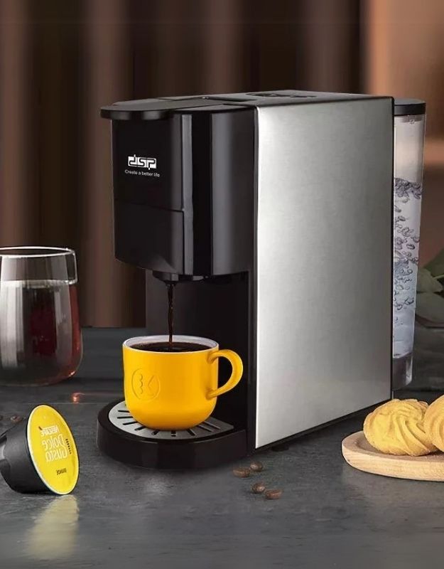 Capsule coffee machine brewing espresso into a yellow cup on a kitchen counter.
