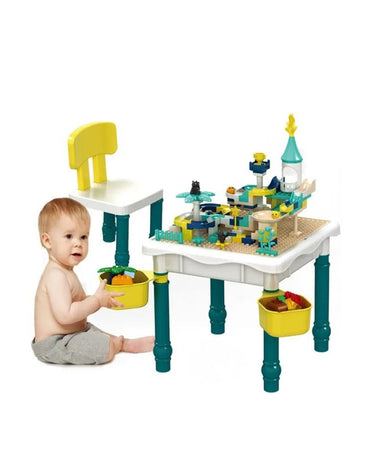 Baby sitting beside the construction table set and playing with building bricks.