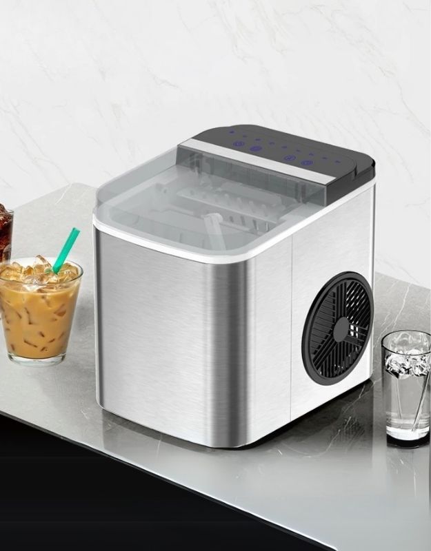 Portable ice maker on a countertop with drinks nearby. Compact stainless steel ice maker on kitchen counter with iced drinks. 