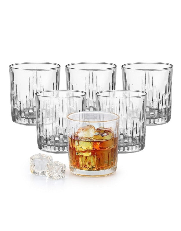 Set of six clear glass tumblers with one containing a drink and ice cubes on a white background.
