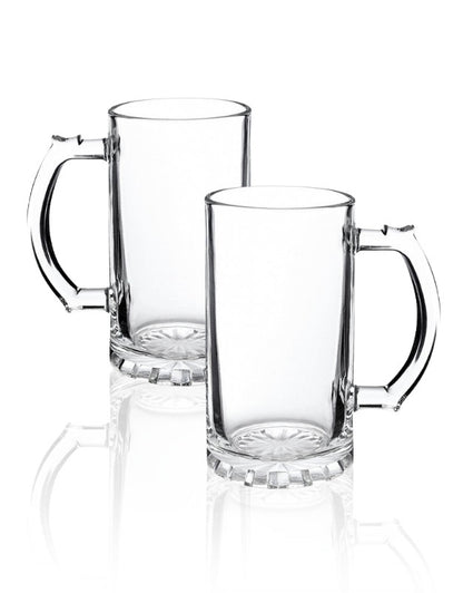 Two clear glass mugs with handles on a white background. Set of two empty clear glass beer mugs with handles on white background.