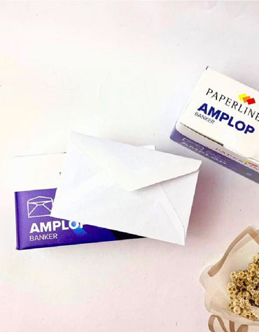 Small white envelope placed on top of a blue Paperline Amplo Banker box, with some dried flowers visible on the side.