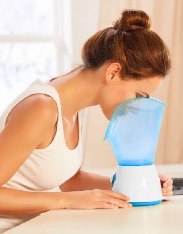 Woman using Enzo EN-8102 face steaming machine warm mist for facial skin care and hydration.