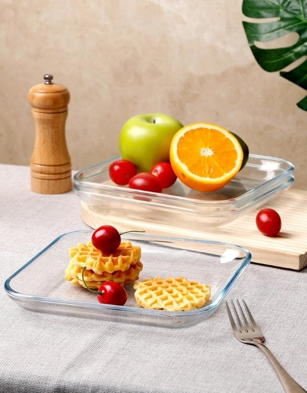 Transparent square glass salad plate serving waffles and cherries on a dining table