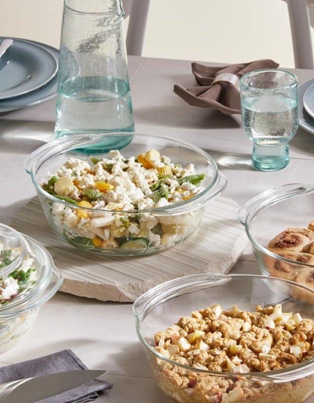 Dining table setup with tempered glass casseroles serving salads and baked dishes