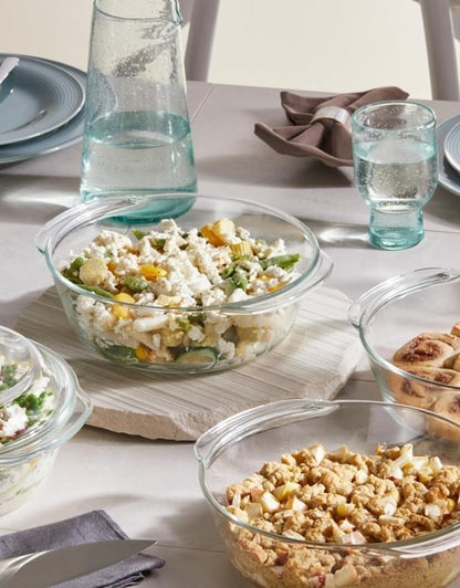 Dining table setup with tempered glass casseroles serving salads and baked dishes