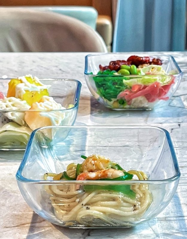 Fenix tempered glass food bowls on dining table, filled with fresh salads and meals
