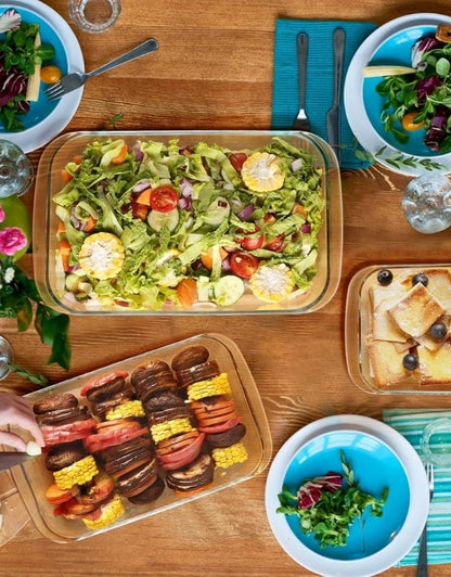 Rectangular glass baking dish set with fresh salad and vegetables served on dining table