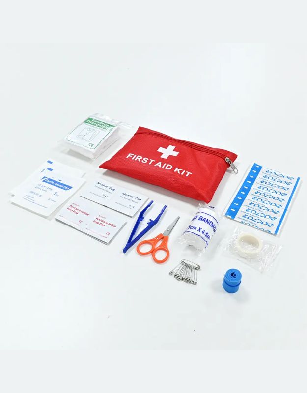 Flat lay of first aid kit supplies including bandages, gauze, tape, and tools.