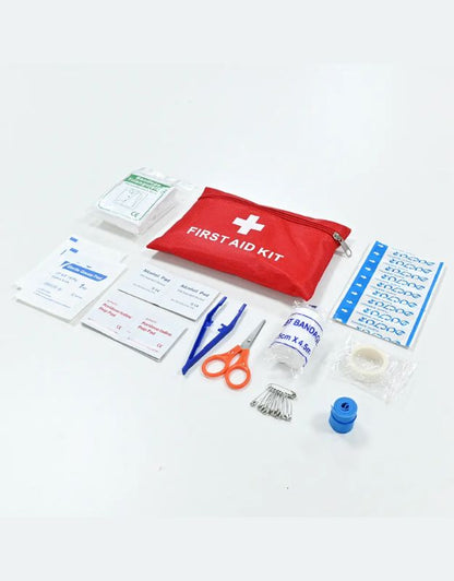 Flat lay of first aid kit supplies including bandages, gauze, tape, and tools.
