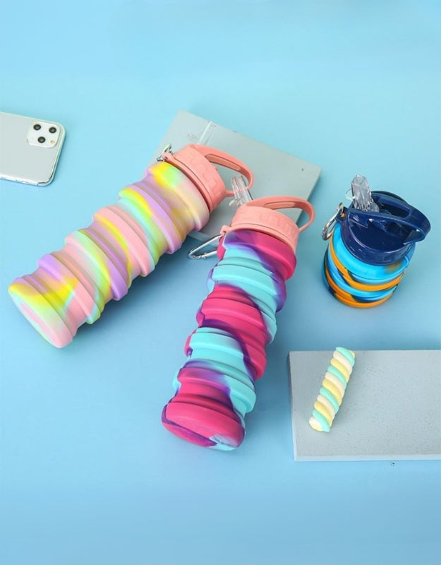Three collapsible water bottles in pastel rainbow, pink-teal, and orange-blue colors, shown fully expanded and collapsed on a blue background.