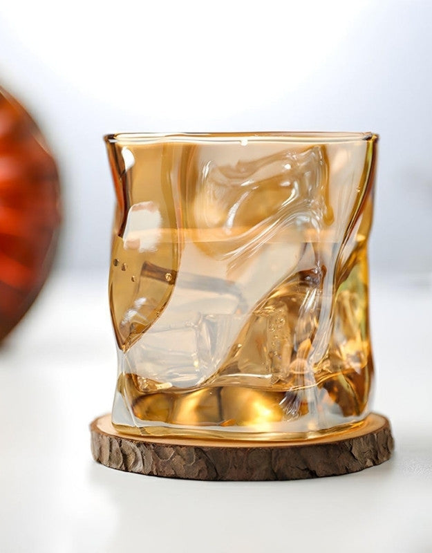 Glass with ice cubes on a wooden coaster against a white background.