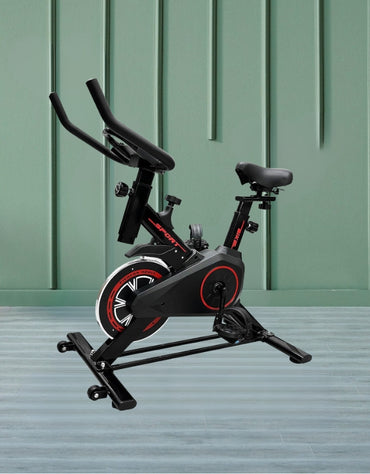 Indoor exercise bike displayed against a green wall and wooden flooring background