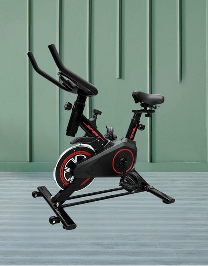 Indoor exercise bike displayed against a green wall and wooden flooring background