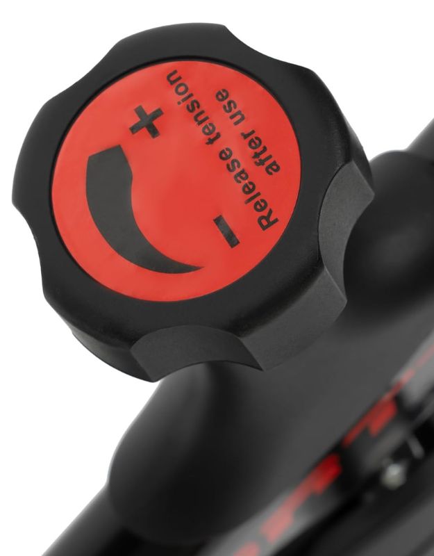 Close-up of the resistance adjustment knob with plus and minus signs for tension control.