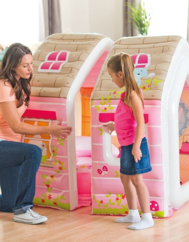 Mother and daughter standing next to an inflatable pink playhouse with cartoon windows.