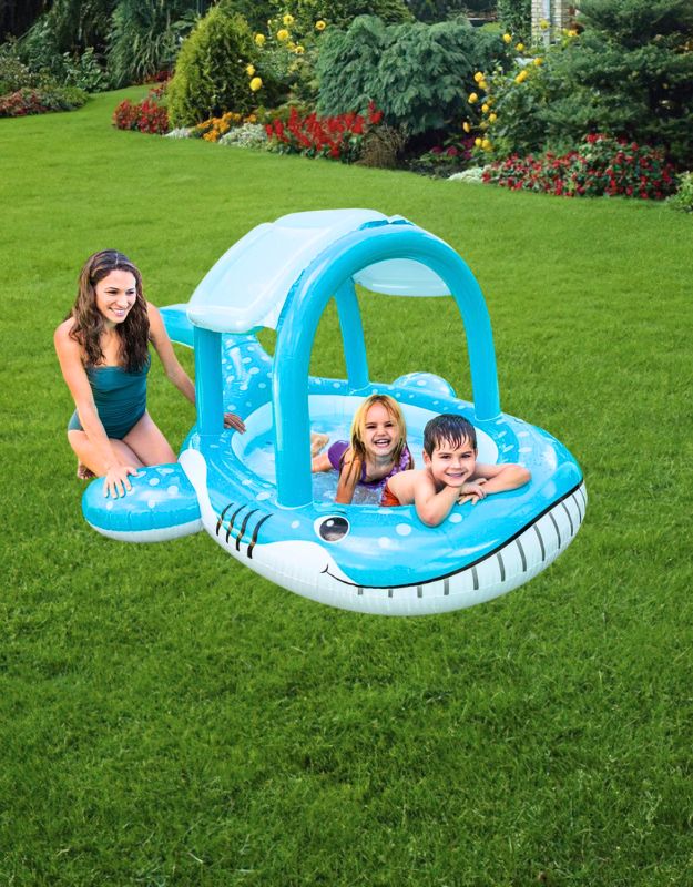 Children playing in the inflatable Intex whale-shaped baby pool with canopy shade, outdoors on grass with a woman supervising.