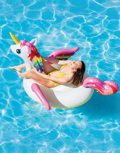 Woman relaxing on giant unicorn pool float with colorful mane and tail in bright blue water.