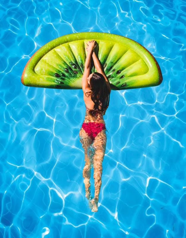 Woman swimming while holding onto Intex 58764EU inflatable kiwi mat in pool.