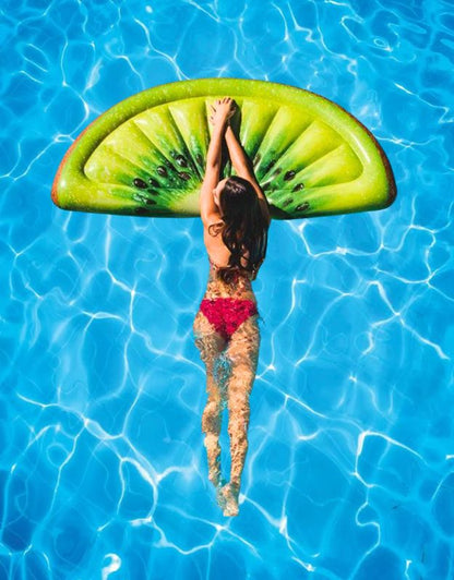 Woman swimming while holding onto Intex 58764EU inflatable kiwi mat in pool.