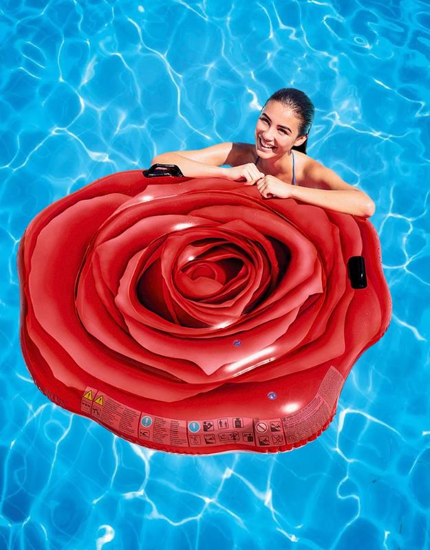 Smiling woman holding Intex 58783EU red rose inflatable float in swimming pool