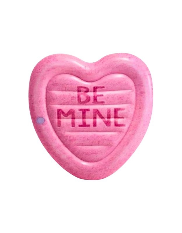 A pink heart-shaped inflatable pool float with the words "BE MINE" printed in bold letters at the center.