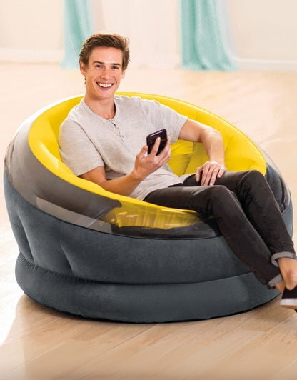 Smiling man sitting comfortably on the Intex 66582NP Empire Yellow Inflatable Chair indoors, holding a smartphone