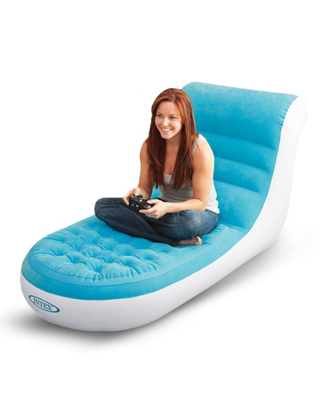 A person sitting on an inflatable sofa that is blue with a white flocked surface.