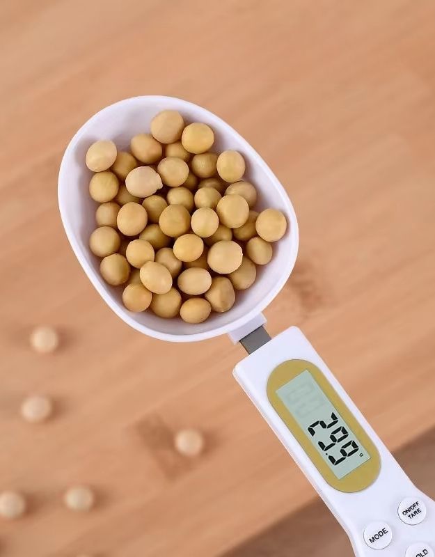 Close-up of digital spoon scale measuring soybeans with accuracy.