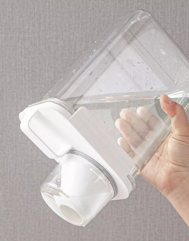 Clear plastic container with white base held by a hand against a gray background. Leakproof airtight food storage container filled with water to test seal.