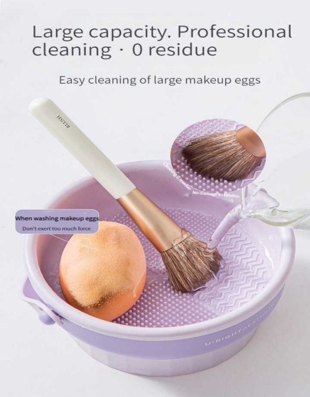Makeup brush and sponge being washed in purple cleaning bucket with textured surface.